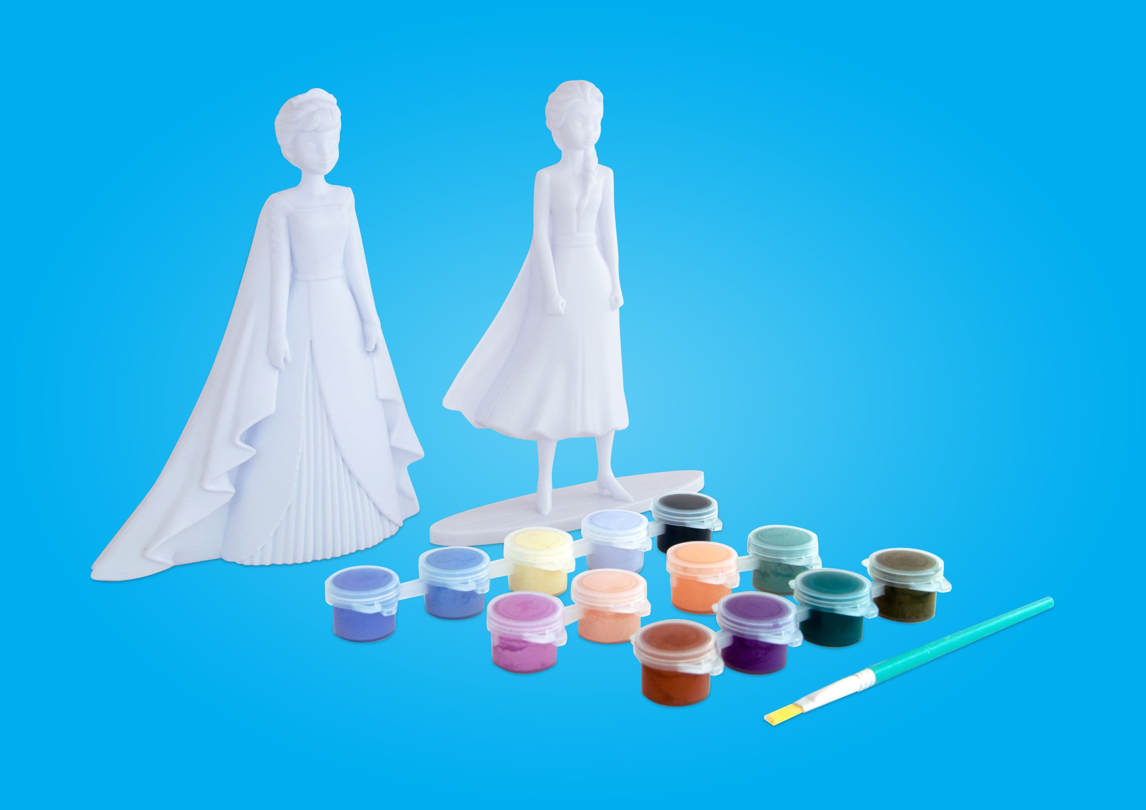 Two unpainted Disney Frozen character figures displayed with twelve small paint pots and a paintbrush on a bright blue background.